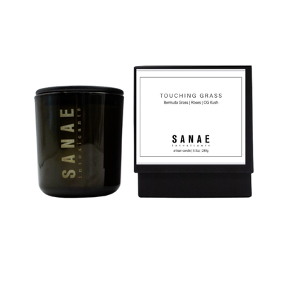 Black candle with 'Sanae' branding and a white label on a white background
