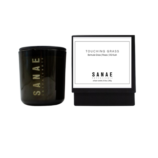 Black candle with 'Sanae' branding and a white label on a white background